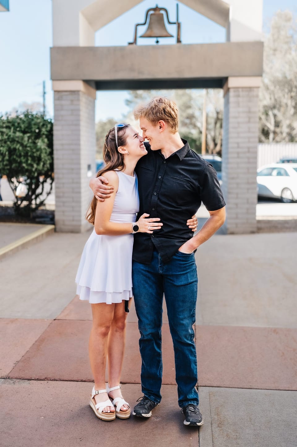 Couple sharing a kiss in front of a white bell tower archway