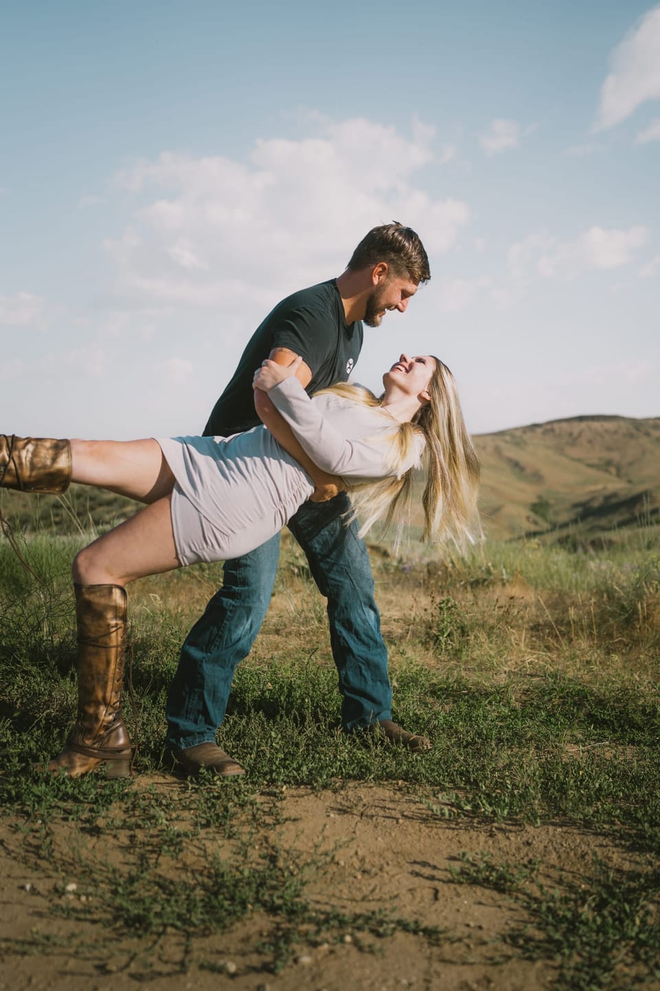 Man playfully lifting his partner on a grassy hill