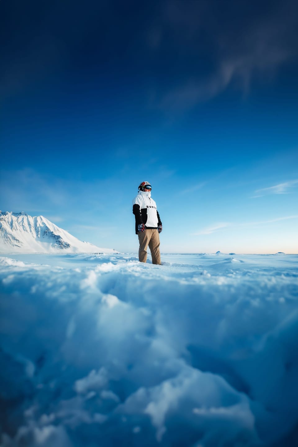 Small figure standing on blue ice under a deep blue sky