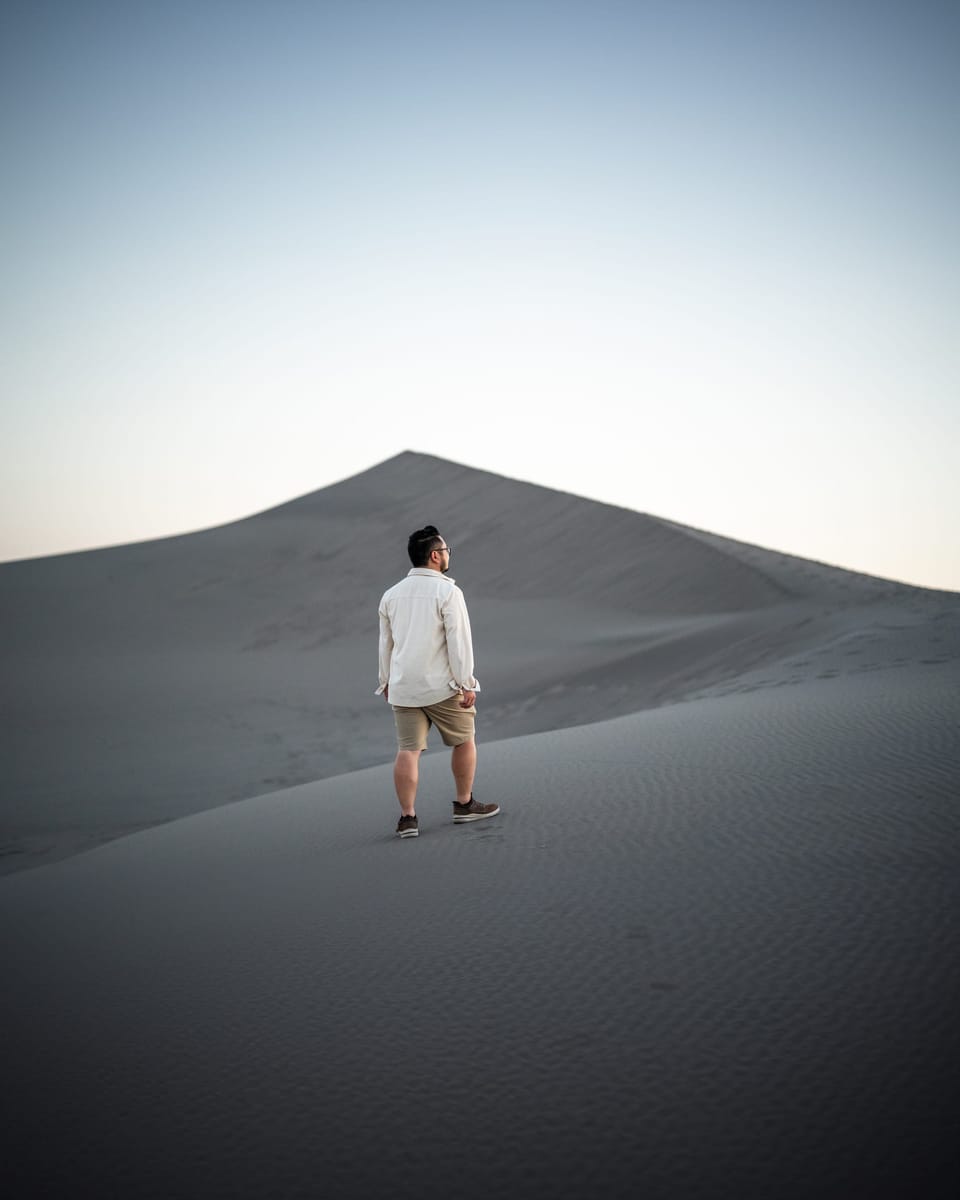 Lone figure standing atop a vast sand dune