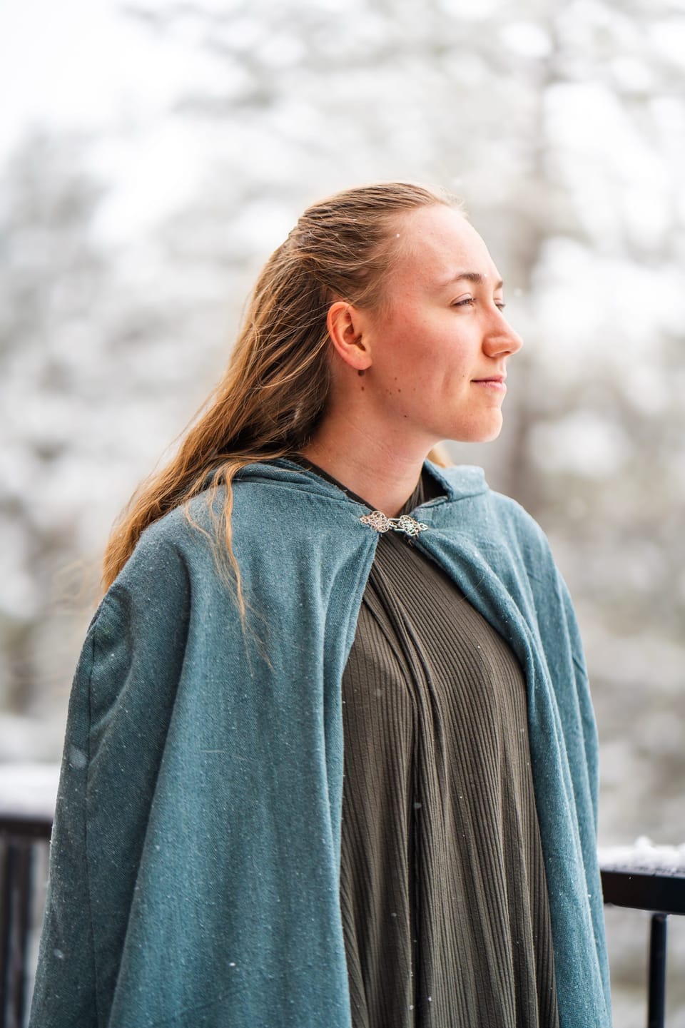Woman in a green cloak gazing into the distance
