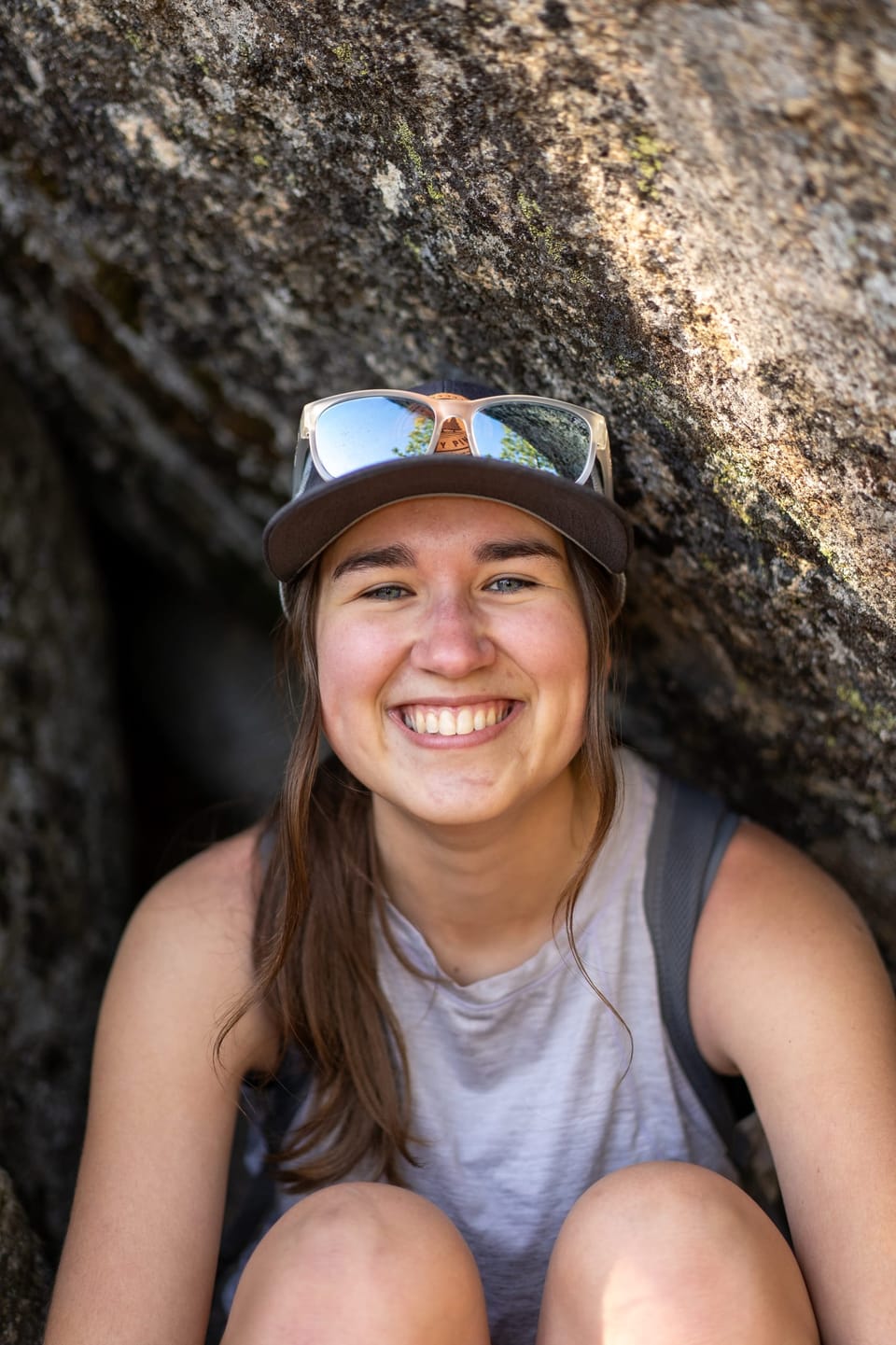 Smiling hiker resting against a large granite boulder