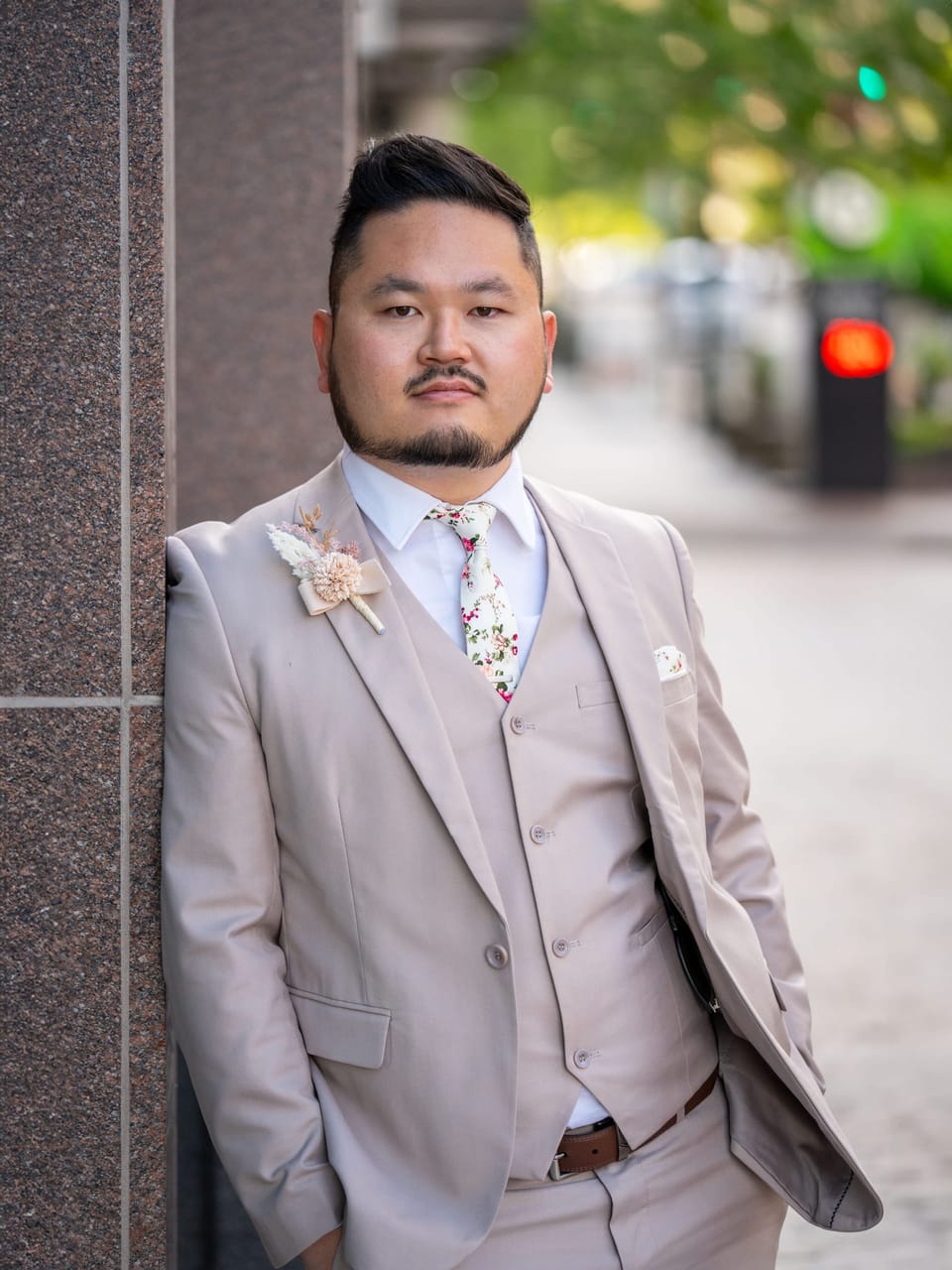 Man in a beige three-piece suit posing by stone columns
