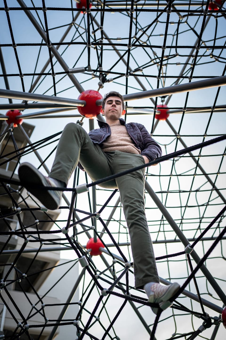 Man climbing a red rope-net play structure