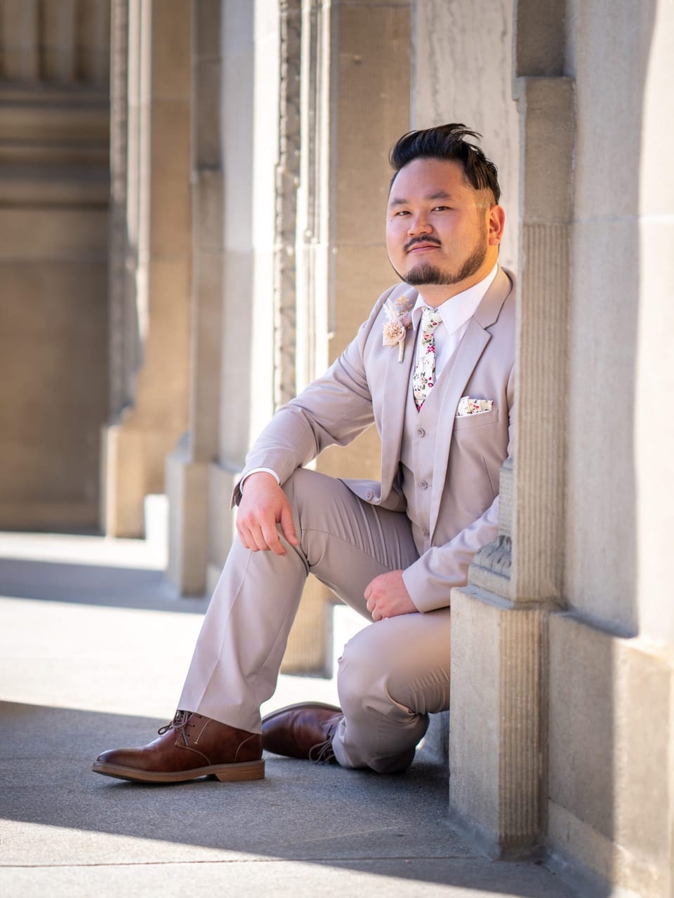 Man in a light suit sitting between stone columns