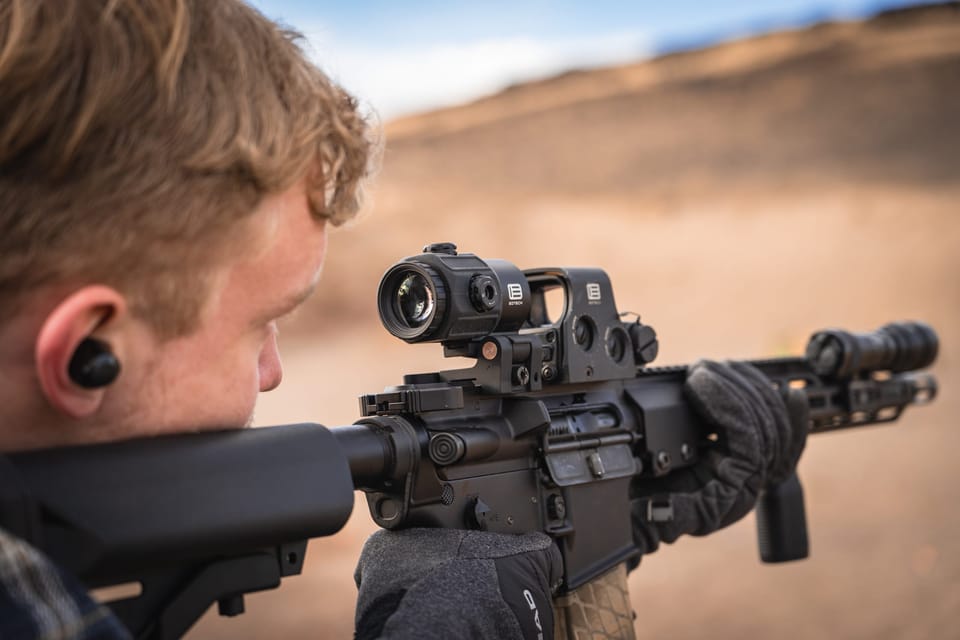 Close-up of a marksman aiming through a scope in the desert
