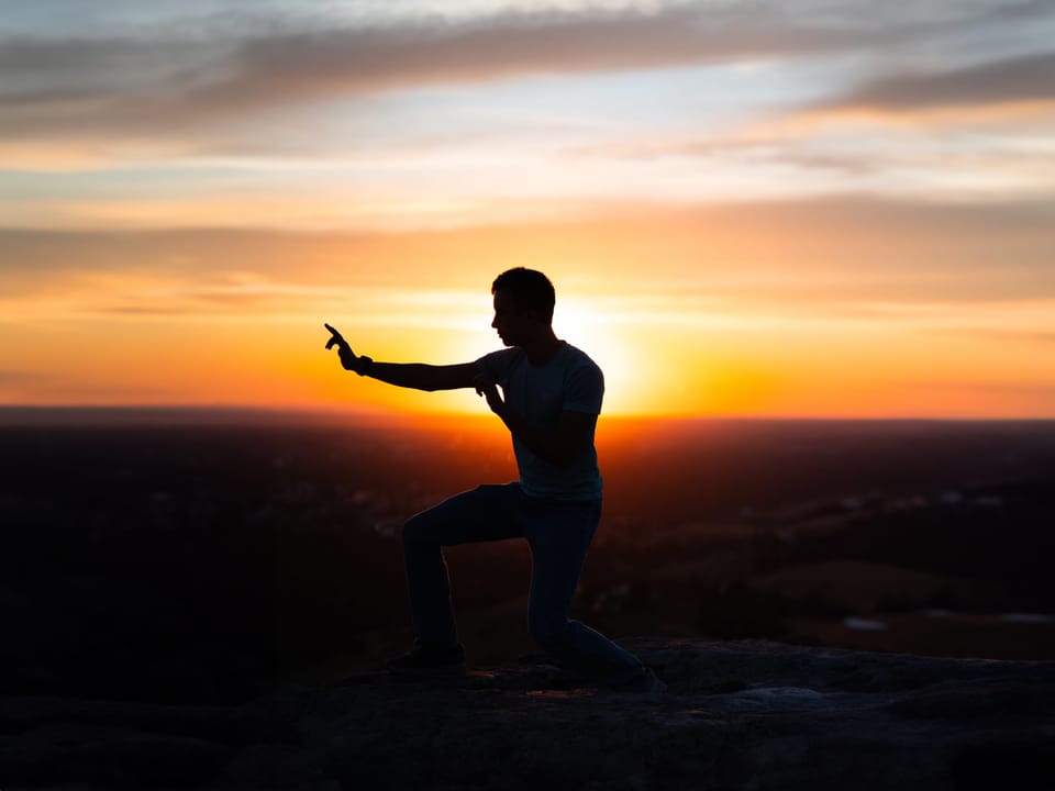 Silhouette of a man in a martial-arts pose against a sunset