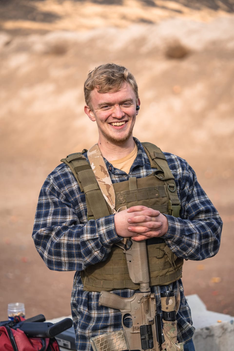 Smiling man in a plaid shirt and vest in the desert