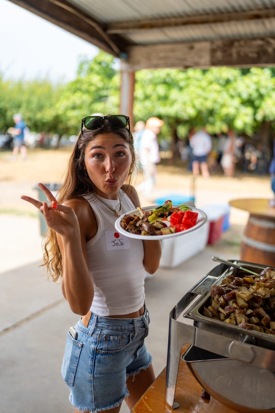 Smiling woman holding a plate at an outdoor gathering