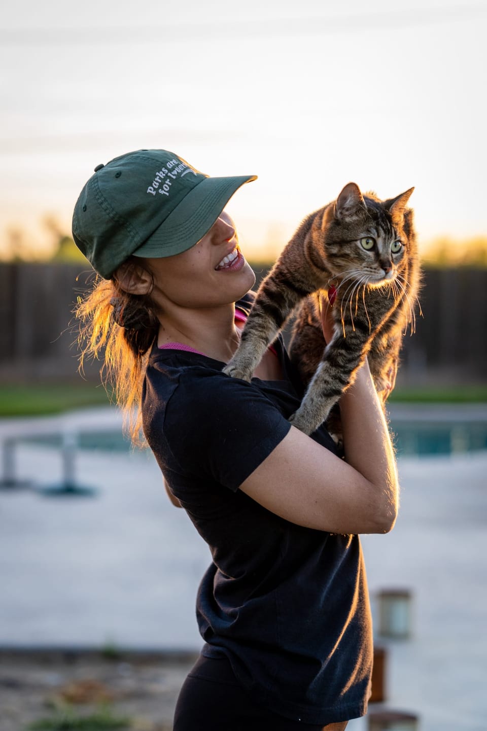 Woman in a green cap holding a cat on her shoulder