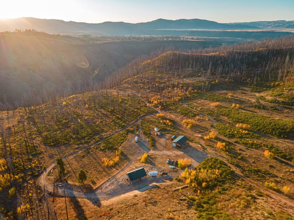 Aerial view of forested hills and a valley in warm golden light