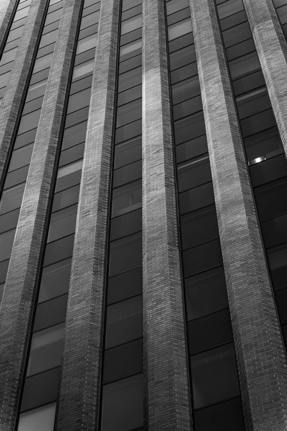 Black-and-white view up a tall ribbed building facade