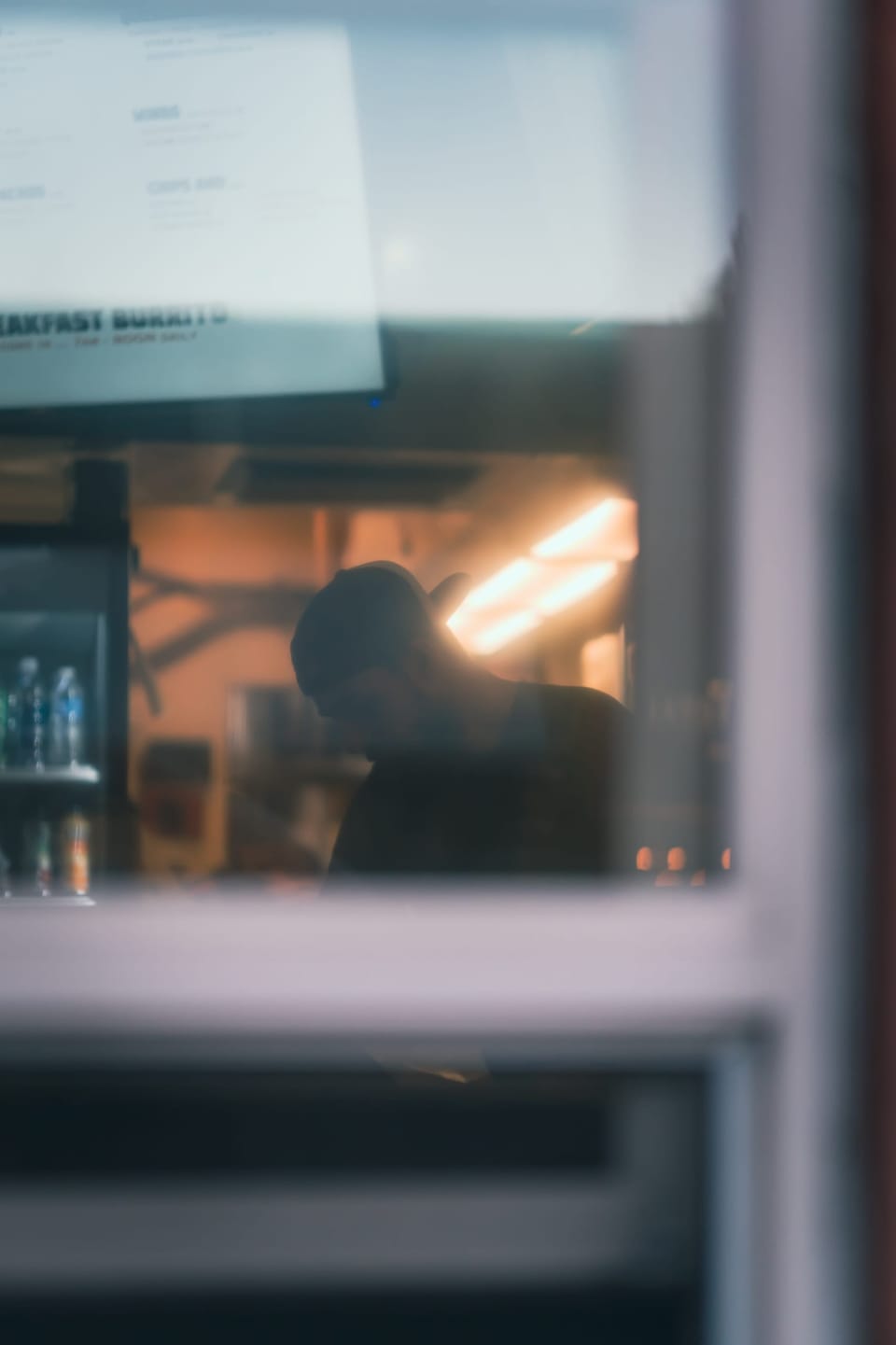 Moody reflection of warm city lights in a cafe window