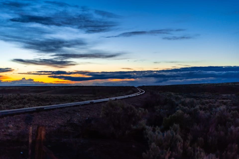 Orange glow on the horizon over flat high-desert sagebrush at dusk