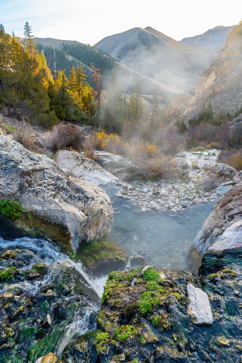 Steaming natural hot spring pools among rocks in a mountain canyon