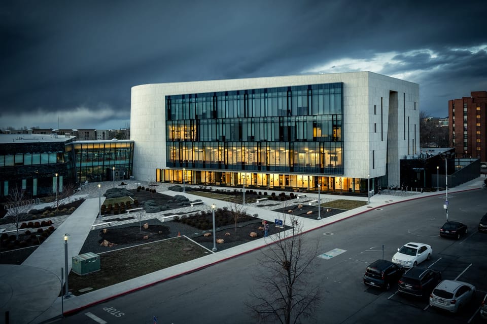 Modern glass building and plaza under a dramatic stormy sky