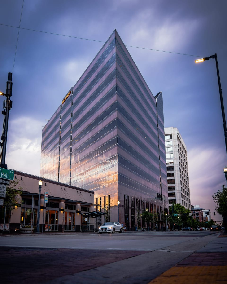 Angular office tower lit against a purple dusk sky