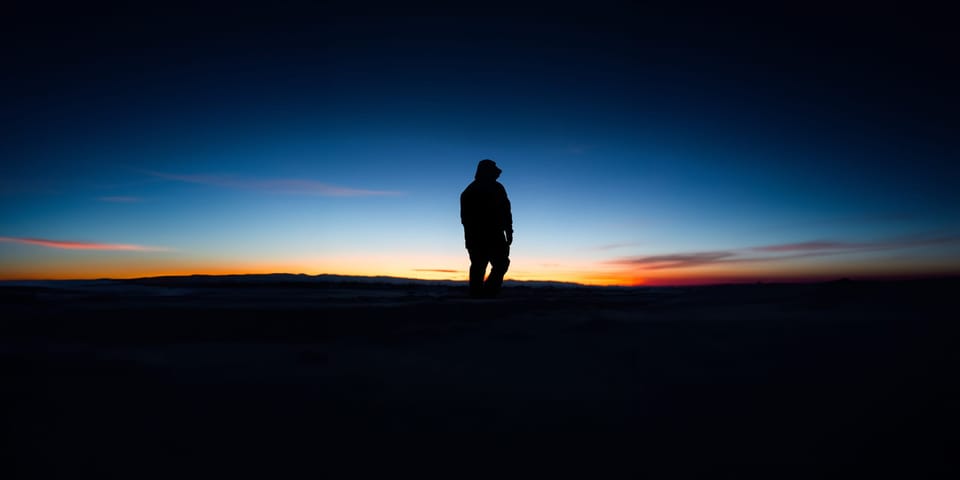 Lone silhouette standing under a deep blue twilight sky