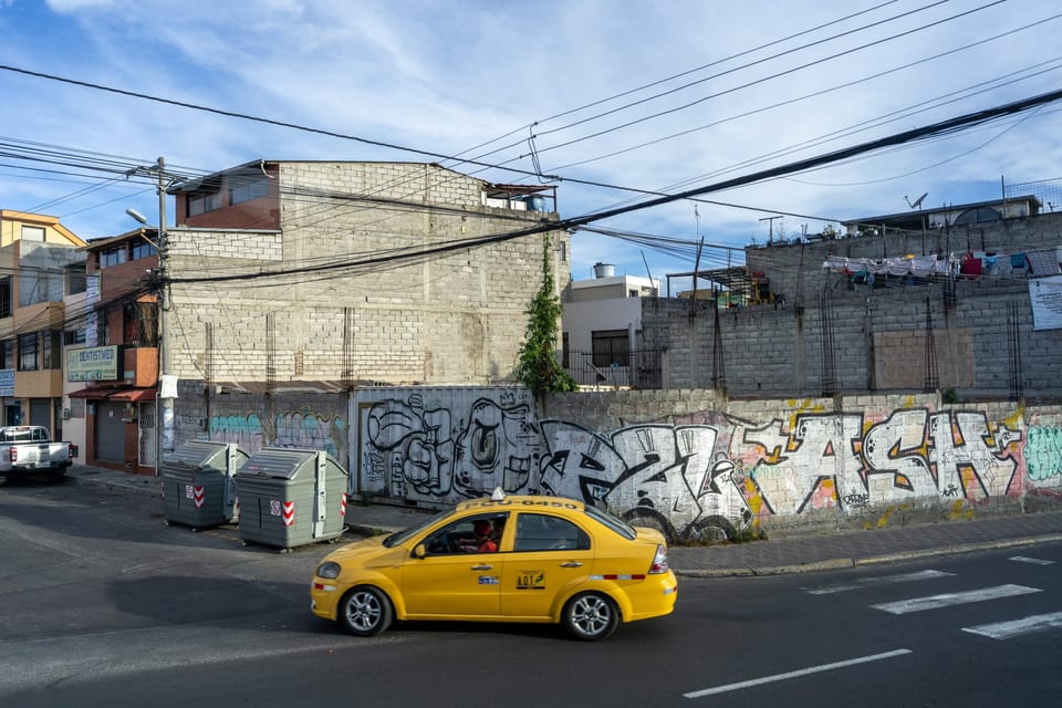 Yellow taxi passing a colorful mural on a sunny city street