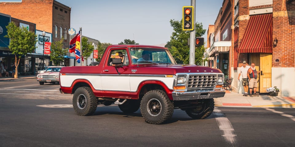 Red and white classic Ford Bronco on a downtown street