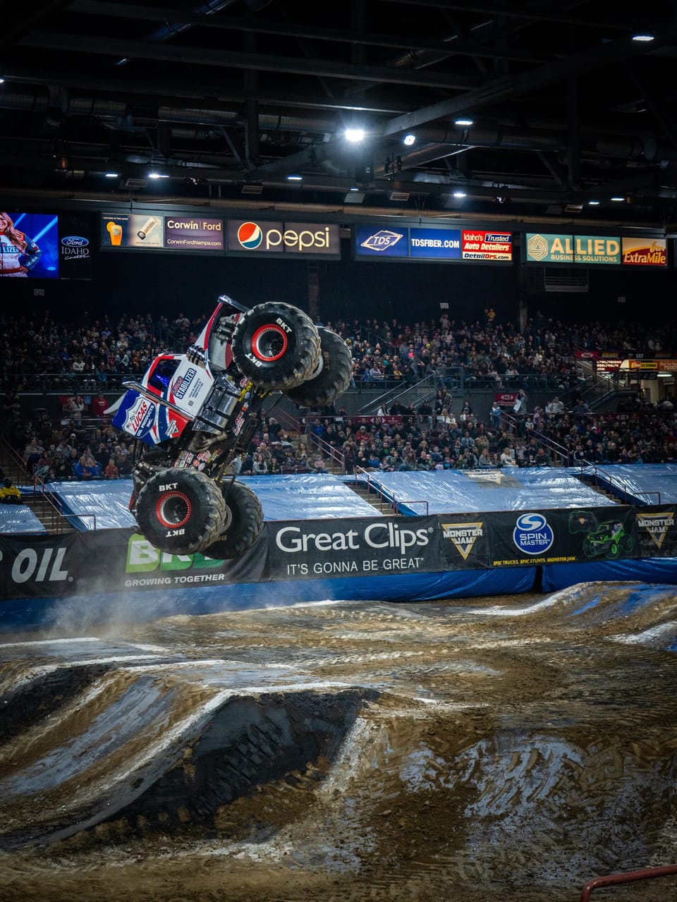 Monster truck flying through the air in a packed arena